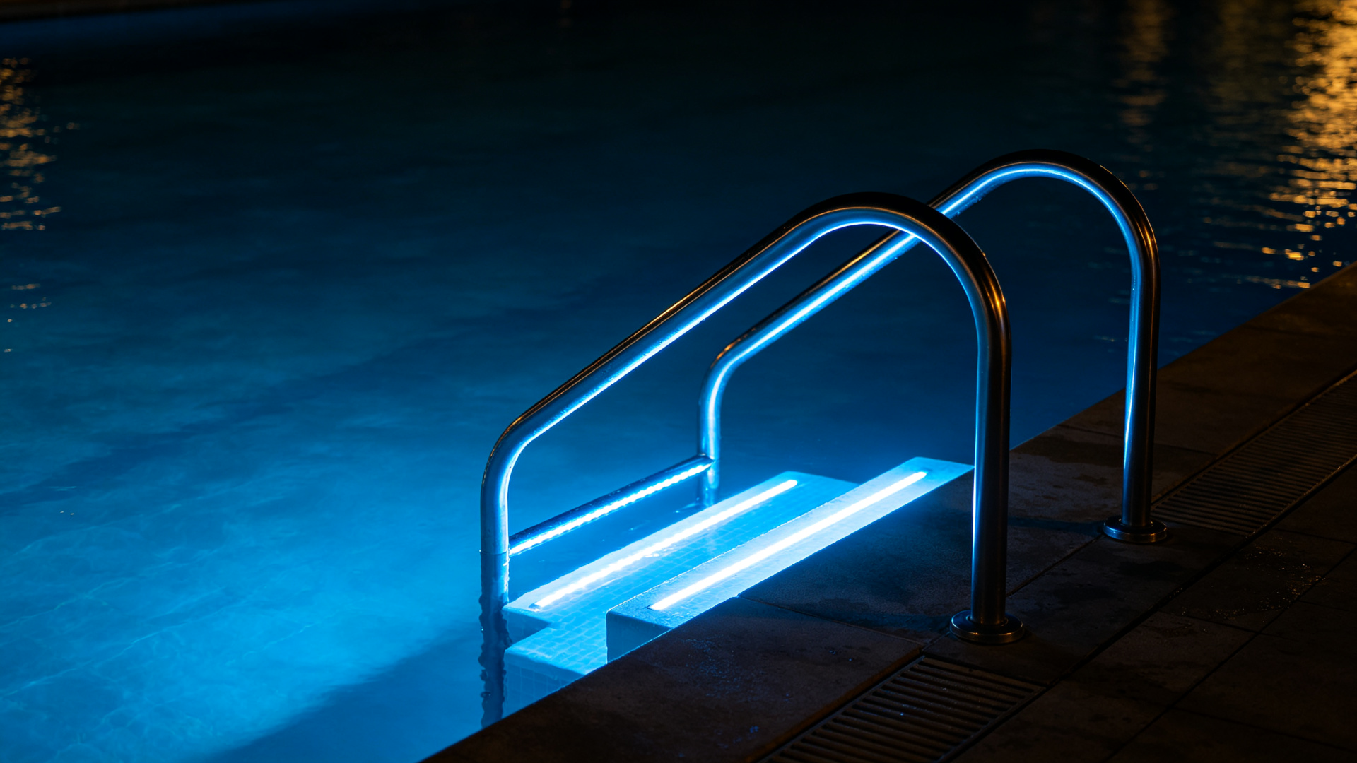 Swimming pool entry steps and ladder illuminated by underwater blue LED strip